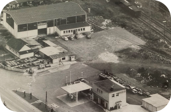 Historic aerial view of an industrial site with several production halls, auxiliary buildings, and adjacent open areas.